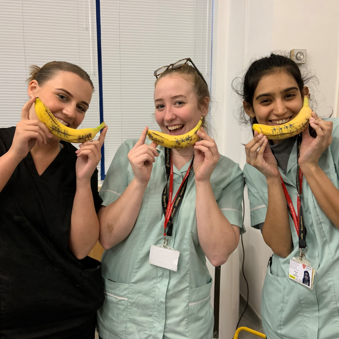 Three female student vet nurses holding bananas that they have used for suture practising