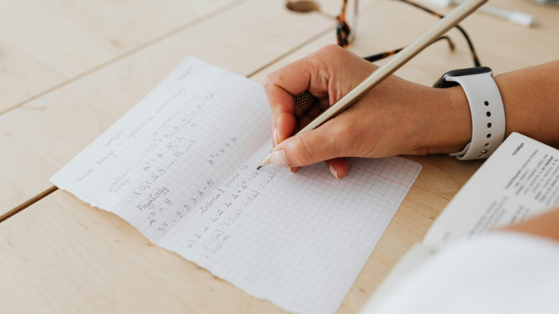 Person carrying out maths calculations on some paper on a desk