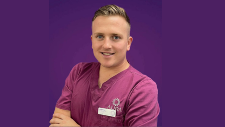 Craig Bailey wearing purply pink scrubs standing against a purple background