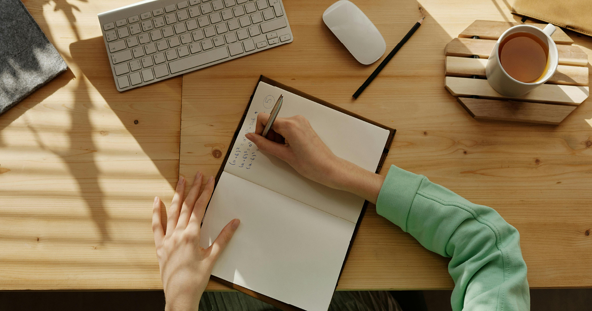 Student studying at a desk writing in a notebook