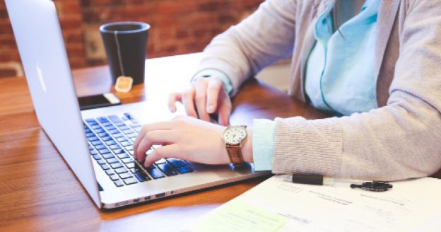Person sitting at a desk typing on a laptop